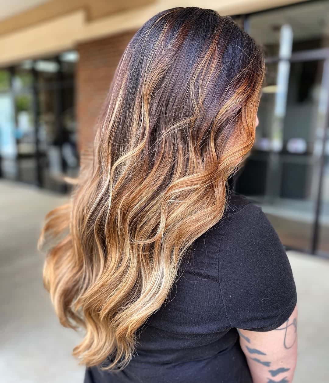 Długie fale z brązowo-blond balayage Długie brązowe włosy z blond balayage ułożone w szerokie fale