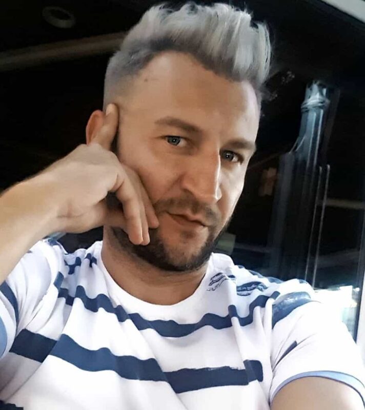 Srebrny quiff z fade i brodą Wysoki srebrny quiff z ciemniejszą nasadą, fade i krótką brodą