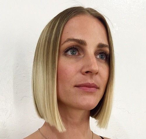 Blond blunt bob z centralnym przedziałkiem Prosty blond bob z przedziałkiem na środku