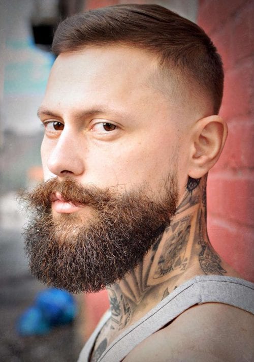 Fade z brodą i stylizowanymi wąsami Krótki fade z pełną brodą i podkręconymi wąsami