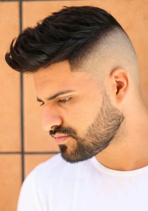Boczny quiff z fade i krótkim zarostem Męski quiff zaczesany na bok z wysokim fade i krótką brodą