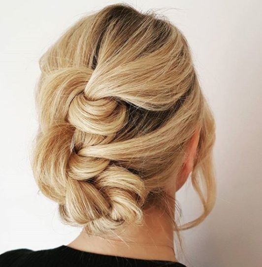 Skręcony elegancki niski kok Skręcone blond włosy uformowane w elegancki niski kok