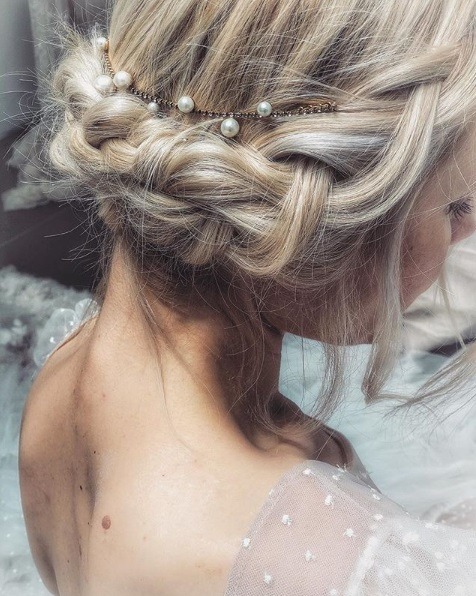Pleciony kok z perłami Pleciony niski kok na blond włosach z perłową ozdobą