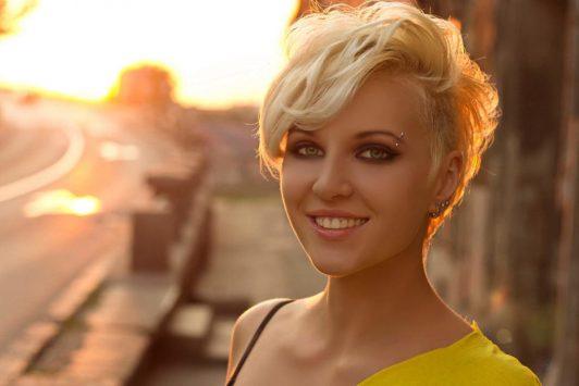 Blond pixie z miękką boczną grzywką Krótka blond fryzura pixie z długą grzywką ułożoną na bok
