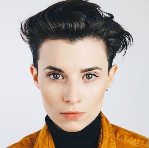 Ciemny androgyniczny quiff z krótkimi bokami Ciemne włosy z krótkimi bokami i mocno uniesioną górą