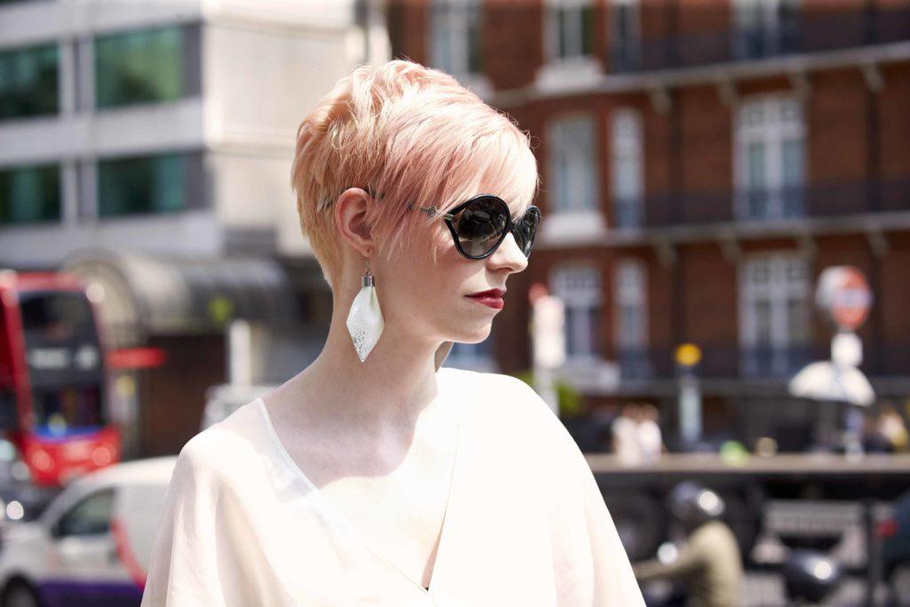 Jasnoróżowe androgyniczne pixie z grzywką Jasnoróżowe krótkie pixie z dłuższą grzywką zaczesaną na bok