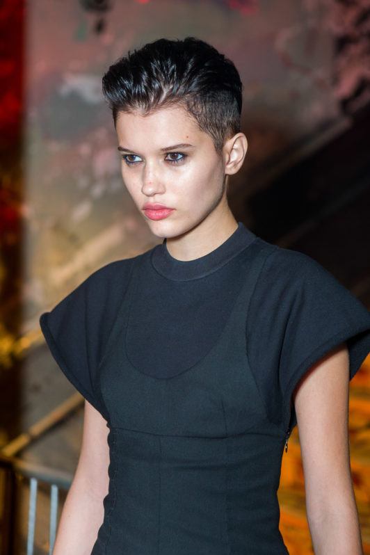 Krótkie androgyniczne cięcie z uniesioną górą Bardzo krótkie ciemne włosy z uniesioną górą i odsłoniętymi bokami